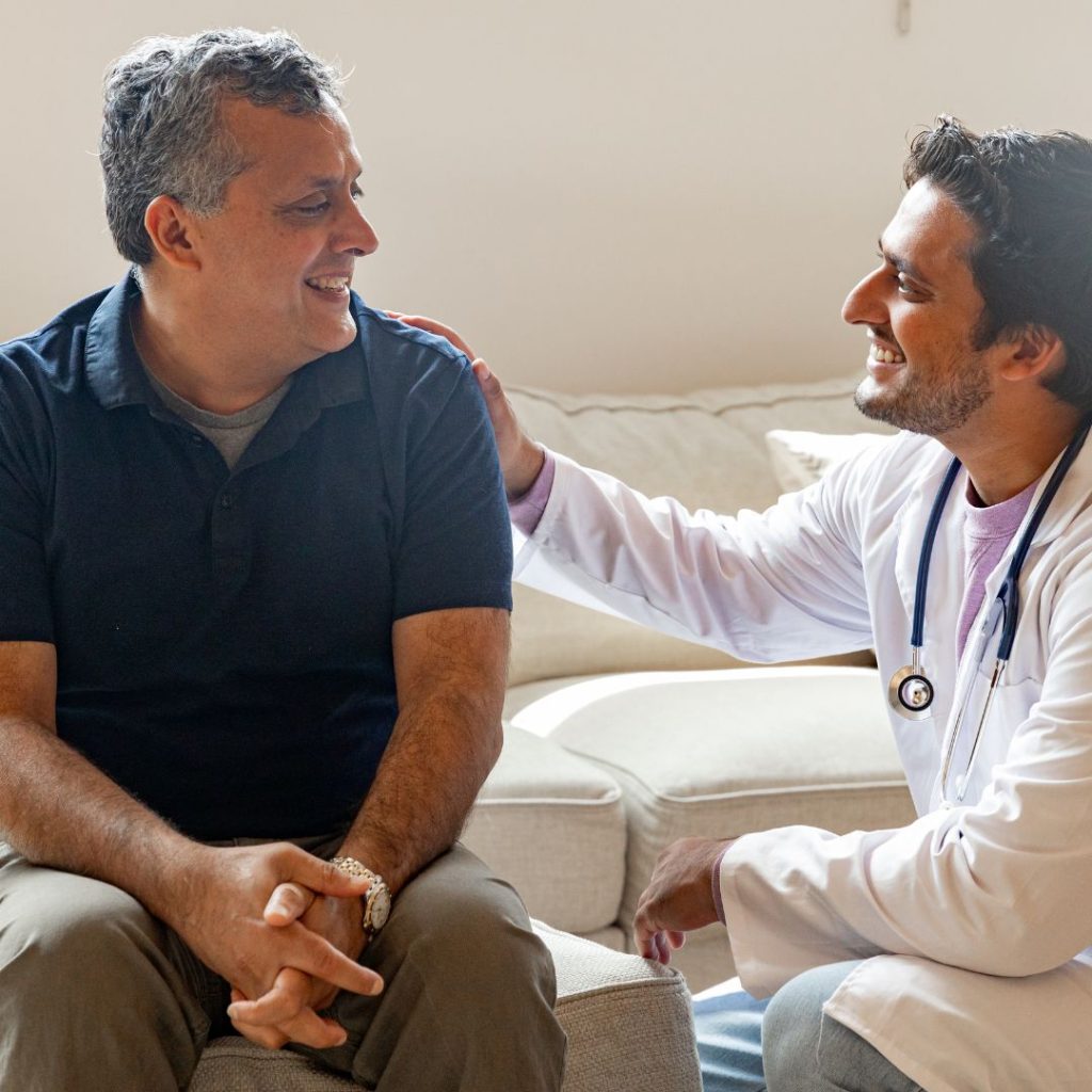 doctor touches man's shoulder sitting down 